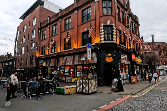Street scene in Manchester’s Northern Quarter featuring Bunny’s Country Club, colourful artwork, outdoor seating and historic red-brick buildings.