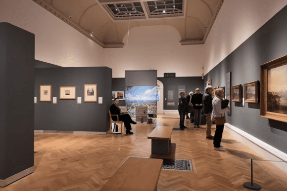Art gallery room at Norwich Castle Museum with visitors viewing framed paintings.