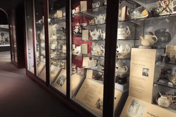 Glass display case filled with decorative teapots and ceramics at Norwich Castle Museum.