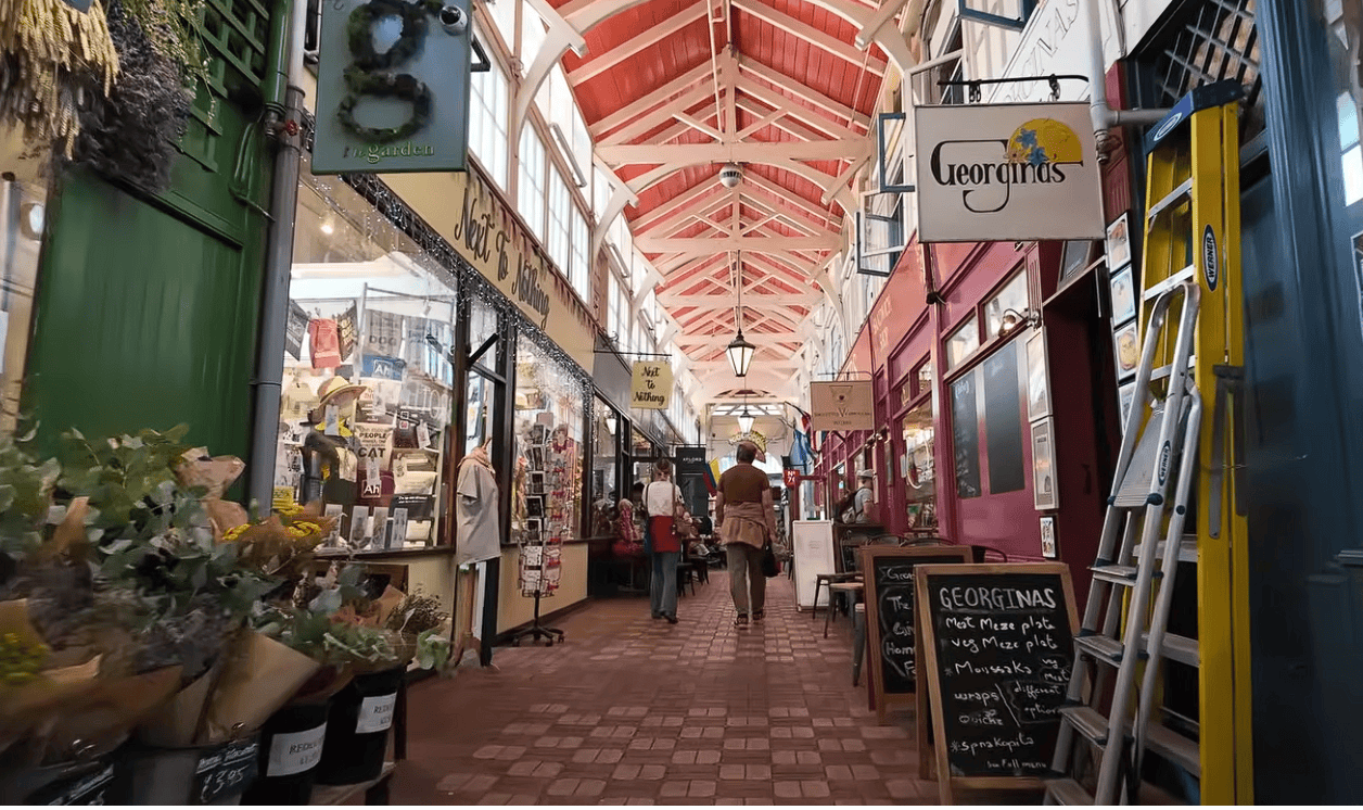 Interior of Oxford Covered Market with independent shops, cafés, colourful storefronts and visitors beneath its historic covered walkway.