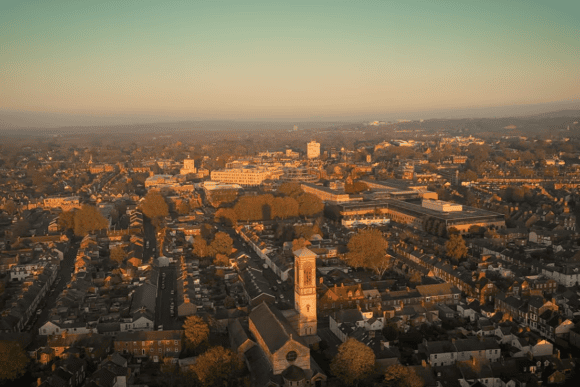 Aerial view across Jericho and central Oxford at golden hour, showing historic streets, rooftops, church towers and the surrounding cityscape.