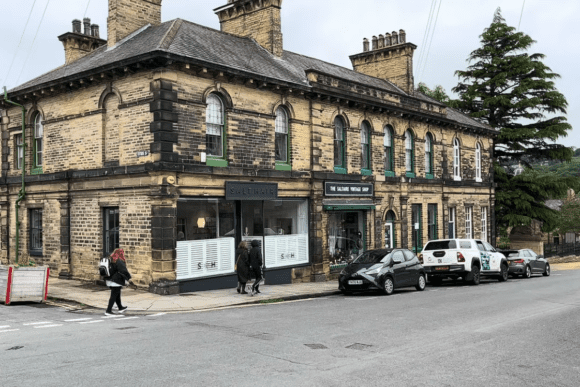 Historic stone building with shops and pedestrians in Saltaire village, West Yorkshire, a UNESCO World Heritage Site.