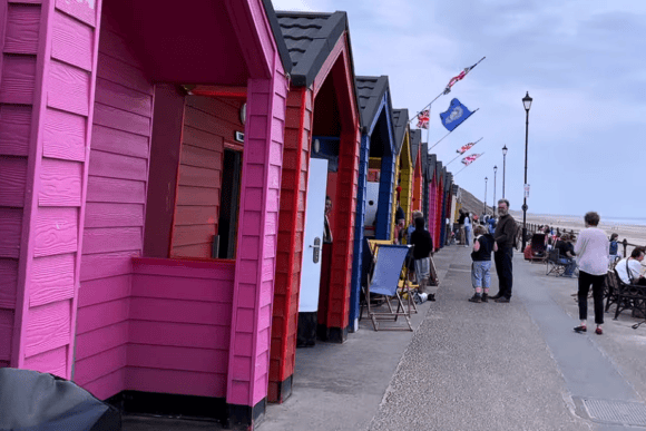 Colourful beach huts lining the promenade at Saltburn Beach in North Yorkshire, with visitors enjoying the seaside and views across the stunning Yorkshire coast.