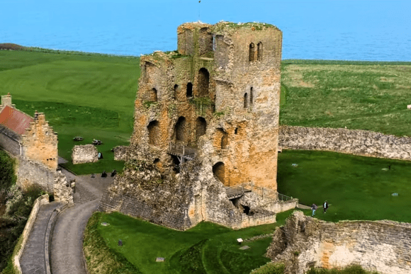 Scarborough Castle ruins overlooking the sea on a grassy headland in North Yorkshire, England.