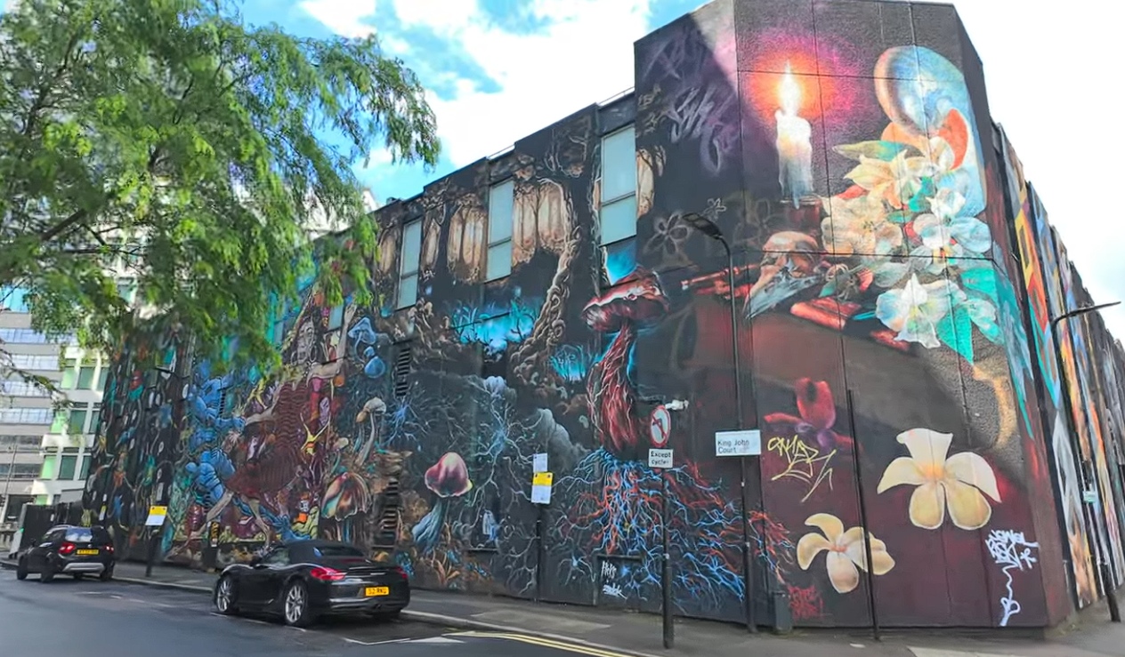 Large colourful street art mural covering a building in Shoreditch, London, featuring flowers, mushrooms and surreal artwork on King John Court.