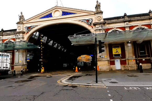 Smithfield Market entrance in London with grand Victorian archway, ornate façade, and street traffic in front.
