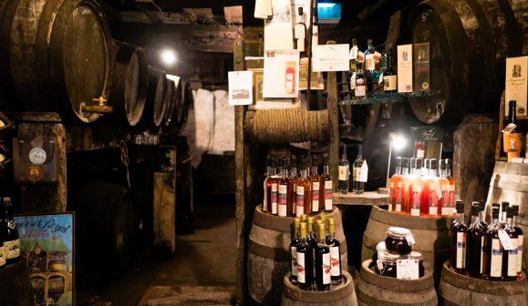 Historic cider cellar at the Somerset Cider Brandy Company featuring traditional oak barrels, wooden casks, and bottles of Somerset cider and apple brandy on display.