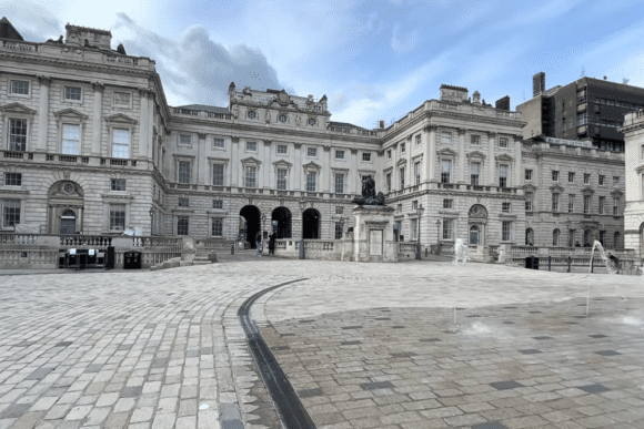 Somerset House courtyard London with fountains, statue, and grand neoclassical buildings under a cloudy sky.