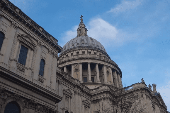 St Paul’s Cathedral London dome viewed from below, showcasing its iconic Baroque architecture against a blue sky.