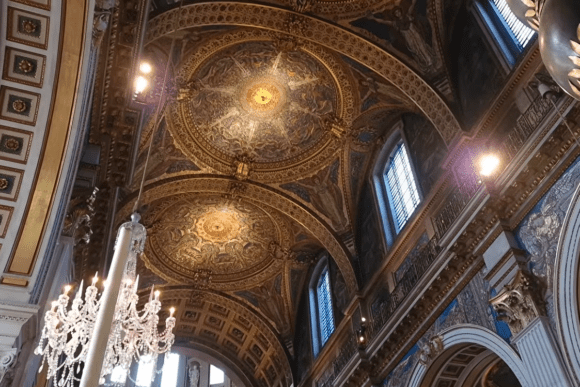 Ornate ceiling inside St Paul’s Cathedral London with gilded mosaics, chandeliers, arches, and detailed Baroque artwork.