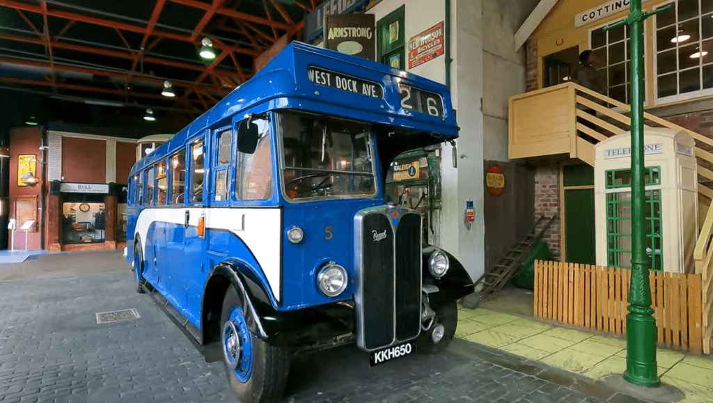 Vintage blue double-decker-style bus displayed inside the Streetlife Museum of Transport in Hull, recreating a historic British street scene with period shopfronts and transport exhibits.