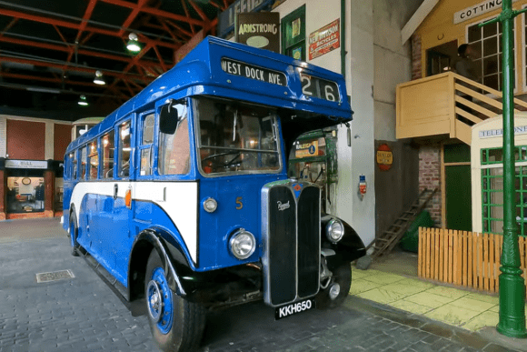 Vintage blue double-decker-style bus displayed inside the Streetlife Museum of Transport in Hull, recreating a historic British street scene with period shopfronts and transport exhibits.