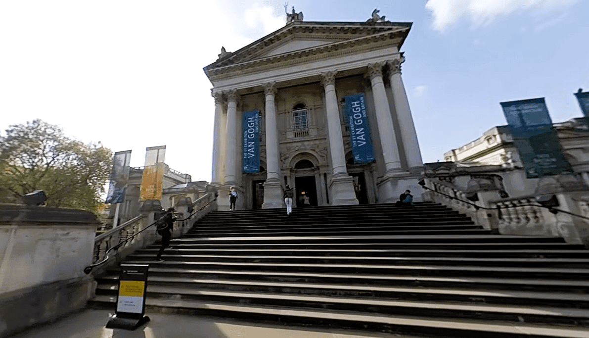 Front entrance of Tate Britain in Millbank, London, featuring grand neoclassical columns, wide stone steps, and exhibition banners.