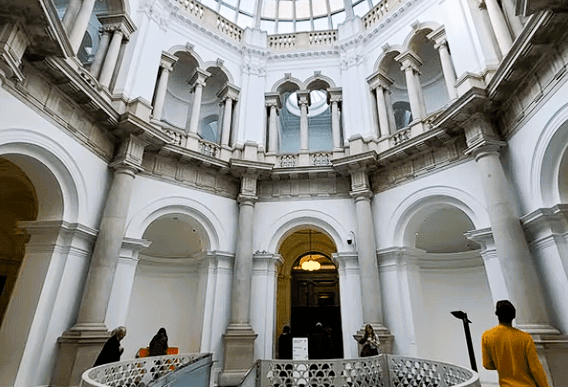 Interior rotunda of Tate Britain in London featuring a glass dome ceiling, classical arches, and elegant white architectural design.