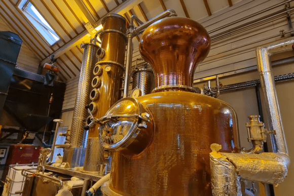 Large traditional copper pot still inside the Cotswolds Distillery, showcasing handcrafted whisky and gin distillation equipment used to produce award-winning English spirits.