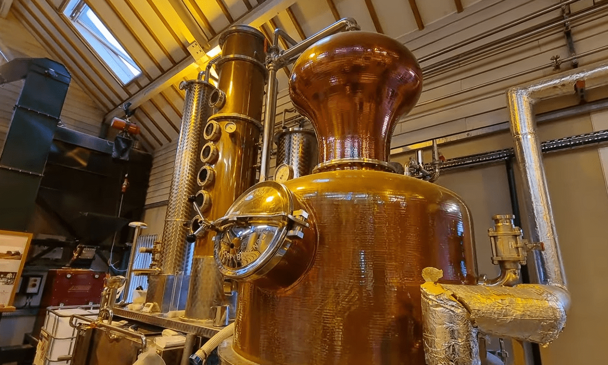 Large traditional copper pot still inside the Cotswolds Distillery, showcasing handcrafted whisky and gin distillation equipment used to produce award-winning English spirits.