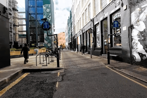 Street scene at the Custard Factory in Digbeth, Birmingham, featuring large murals, independent venues, industrial buildings and colourful urban street art.