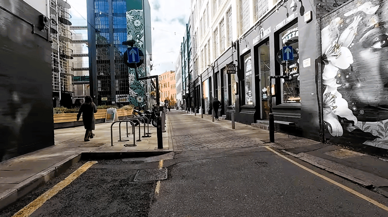 Street scene at the Custard Factory in Digbeth, Birmingham, featuring large murals, independent venues, industrial buildings and colourful urban street art.