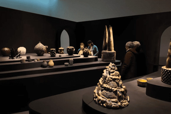 Contemporary ceramics exhibition at The Hepworth Wakefield featuring sculptural pottery, handcrafted vessels, and visitors viewing modern ceramic artworks in a dramatic gallery setting.
