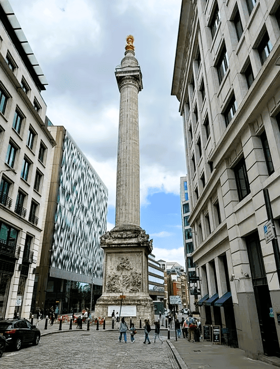 The Monument to the Great Fire of London standing tall in the City of London between modern buildings and historic streets.