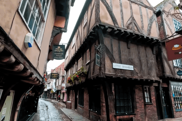 Historic timber-framed buildings lining The Shambles medieval street in York with narrow cobbled lanes and traditional shopfronts.