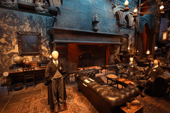 Gryffindor Common Room set at Warner Bros. Studio Tour London – The Making of Harry Potter, featuring a grand fireplace, leather sofas, Hogwarts uniforms, and authentic props from the Harry Potter films.