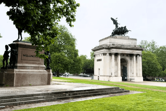Wellington Arch and the Duke of Wellington statue in London surrounded by green parkland, featuring the famous bronze quadriga sculpture atop the historic arch.