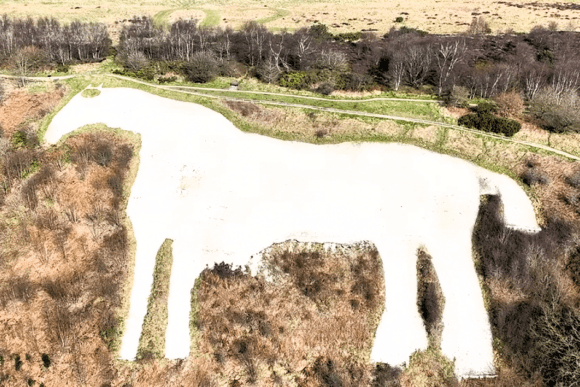 Aerial view of the White Horse of Kilburn carved into the hillside of the North York Moors, surrounded by woodland and open countryside.