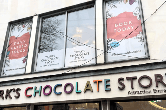 Exterior entrance to York’s Chocolate Story in York city centre featuring colourful signage and promotional windows for guided chocolate tours.