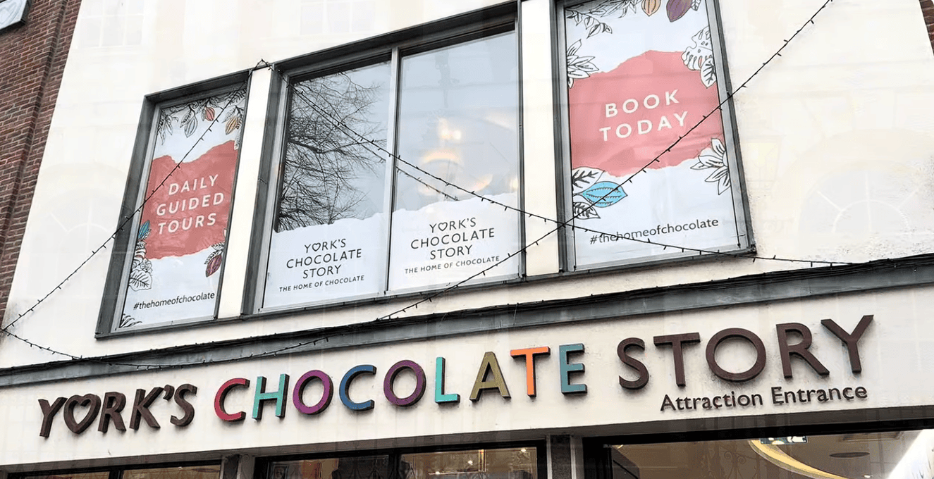 Exterior entrance to York’s Chocolate Story in York city centre featuring colourful signage and promotional windows for guided chocolate tours.