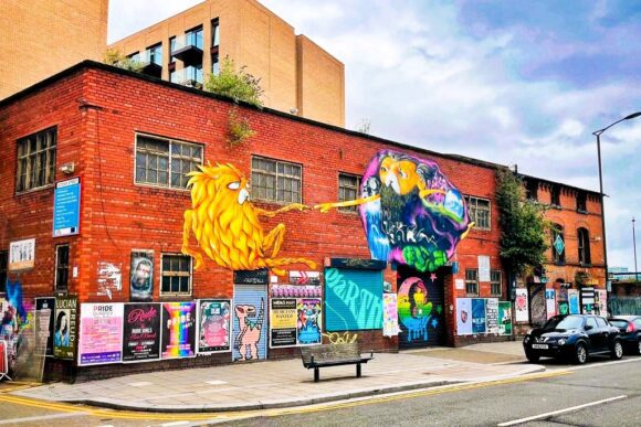 Colourful street art murals covering a red-brick building in Liverpool’s Baltic Triangle, a creative district known for urban art and independent culture.