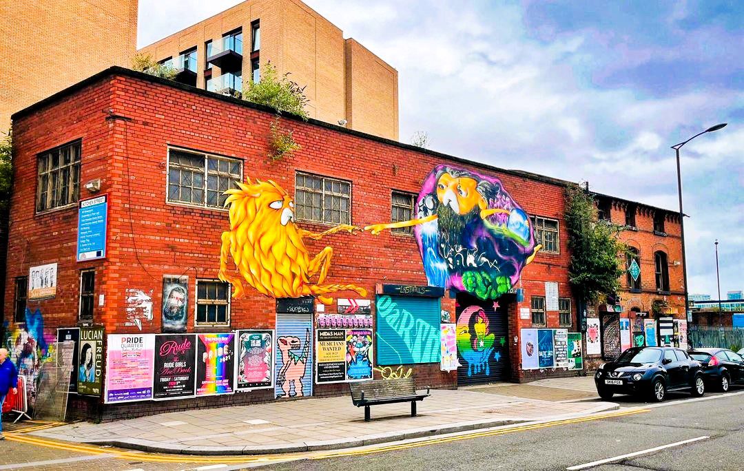 Colourful street art murals covering a red-brick building in Liverpool’s Baltic Triangle, a creative district known for urban art and independent culture.
