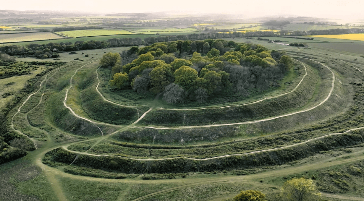 Aerial view of Badbury Rings Iron Age hill fort with concentric earthworks and woodland in Dorset