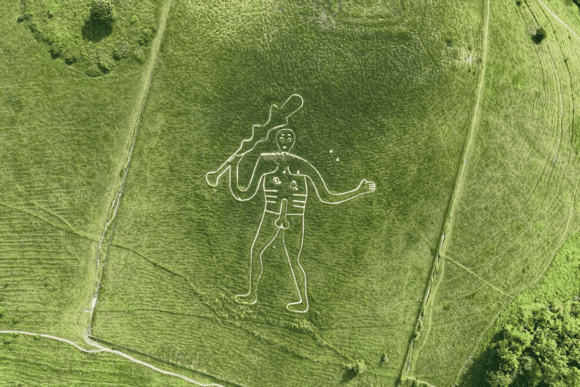 Aerial view of the Cerne Abbas Giant chalk hill figure carved into a green hillside, depicting a large naked man holding a club.