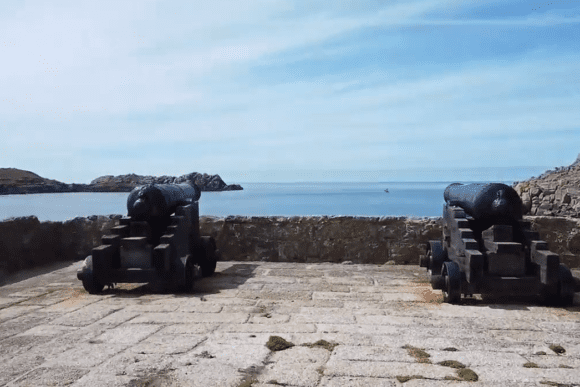 Historic cannons positioned on the stone battery at Cromwell’s Castle overlooking the sea.