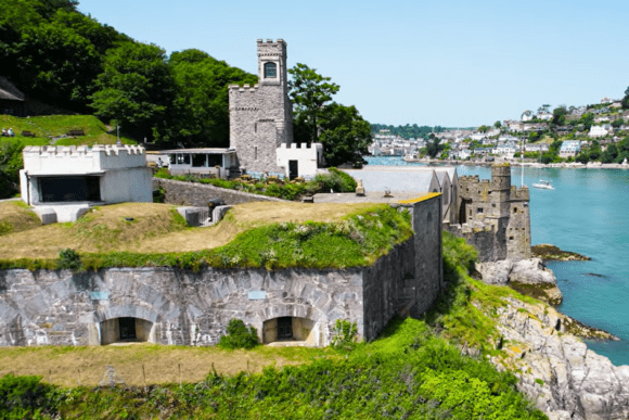 Dartmouth Castle perched on a rocky headland overlooking the River Dart, with towers, gun batteries, and the town beyond.