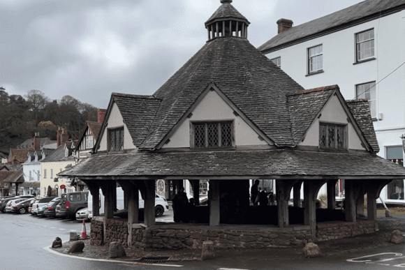 Historic timber-framed Dunster Yarn Market with a shingled roof and central lantern in Dunster village.