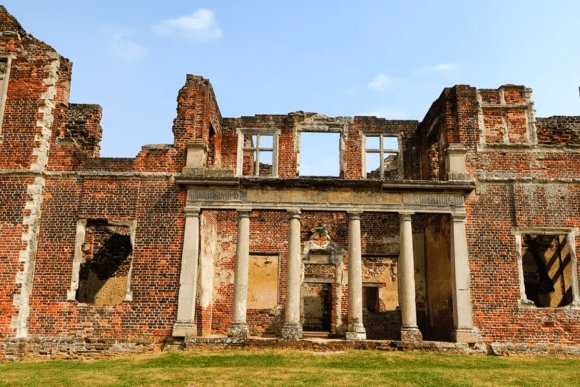 Ruins of Houghton House with red brick walls and classical columns in Bedfordshire.