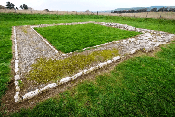 Stone foundations of the Roman temple at Jordan Hill surrounded by grass in Dorset.