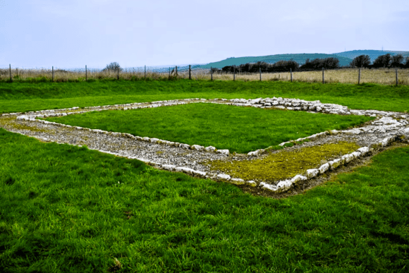 Rectangular stone foundations of Jordan Hill Roman Temple set in grassy countryside near Weymouth.