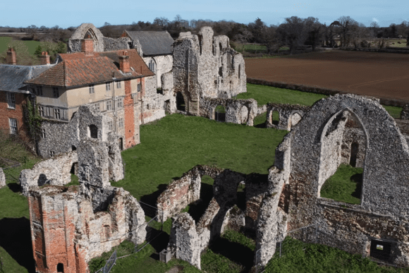 Aerial view of Leiston Abbey ruins with stone walls, arched windows, and surrounding countryside.