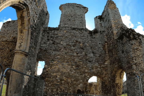 Stone ruins of Leiston Abbey with tall weathered walls, arched openings, and blue sky visible above.