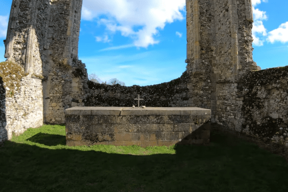 Stone altar with a cross inside Leiston Abbey ruins, surrounded by tall broken walls and open sky.
