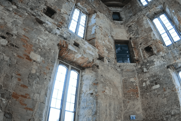 Interior of Lulworth Castle showing tall windows, exposed stone walls, and weathered brickwork.