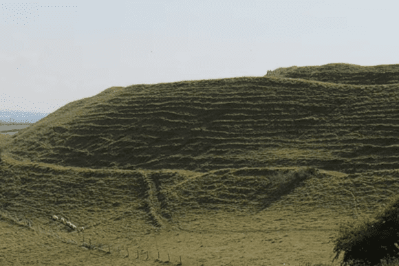 Close view of Maiden Castle’s grassy ramparts showing layered earthwork terraces.