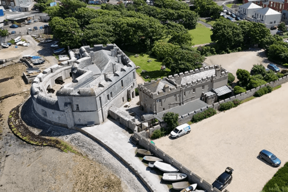 Aerial view of Portland Castle in Dorset, England, showing the historic coastal fortress beside the shoreline with surrounding buildings and greenery.