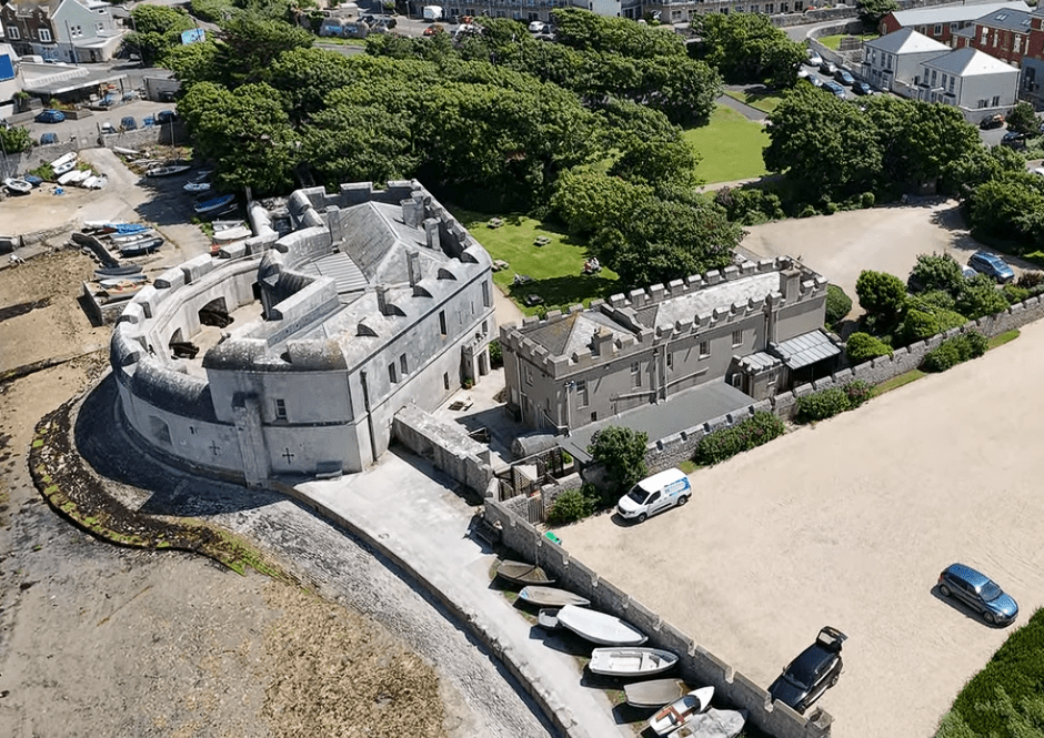 Aerial view of Portland Castle in Dorset, England, showing the historic coastal fortress beside the shoreline with surrounding buildings and greenery.