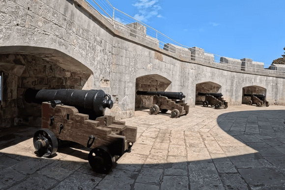 Historic cannons inside Portland Castle in Dorset, England, positioned along curved stone walls overlooking the coast.