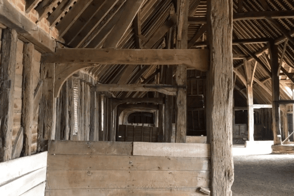 Interior detail of Prior’s Hall Barn in Essex, England, featuring timber beams, wooden partitions, and medieval barn framework.