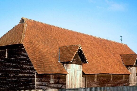 Prior’s Hall Barn in Widdington, Essex, England, featuring a large timber-framed structure with a red tiled roof and traditional rural setting.